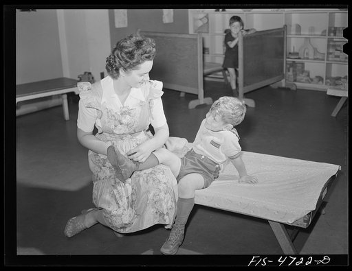 Queens, New York. Nursery school at the Queensbridge housing project. Dressing a child after a nap