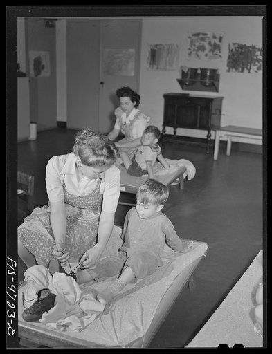 Queens, New York. Nursery school at the Queensbridge housing project. Dressing a child after a nap