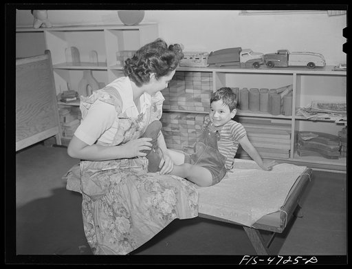 Queens, New York. Nursery school at the Queensbridge housing project. Dressing a child after a nap