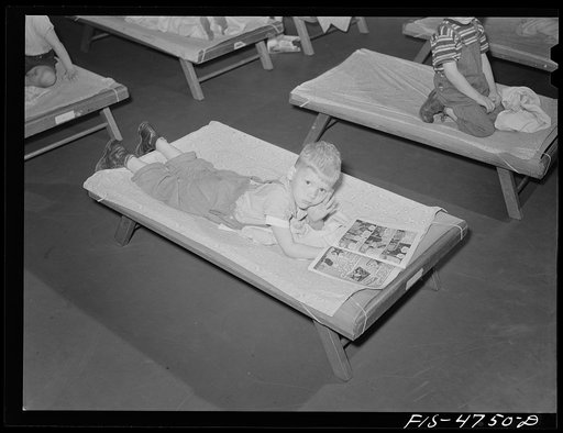 Queens, New York. Nursery school at Queensbridge housing project. Child reading a comic book during rest period