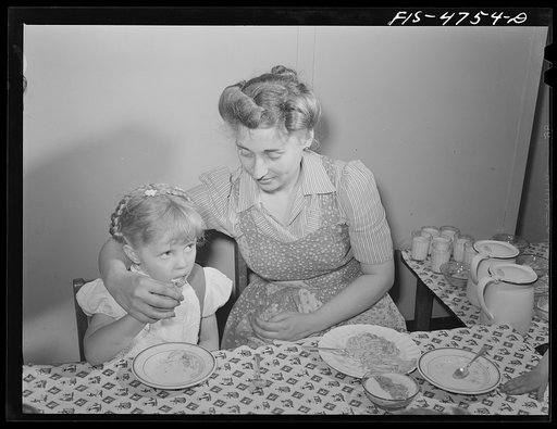 Queens, New York. Nursery school at the Queensbridge housing project. Nursery worker helping children eat lunch