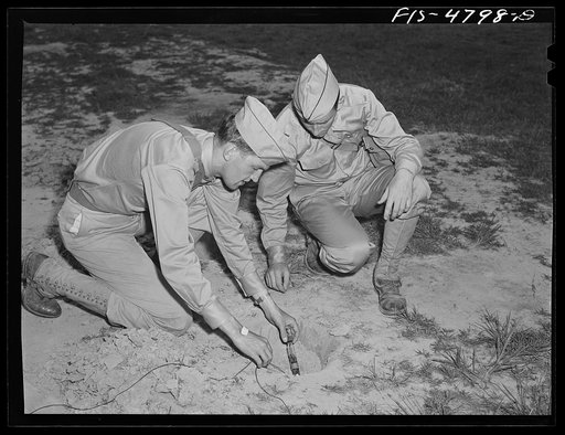 Edgewood Arsenal, Maryland. Gas demonstration. Attaching wiring to a glass tube containing liquid gas. This is later exploded and a group of soldiers are run through the gas to learn its identity by the odor