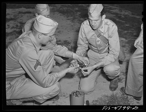 Edgewood Arsenal, Maryland. Gas demonstration. Attaching wiring to a glass tube containing liquid gas. This is later exploded and a group of soldiers are run through the gas to learn its identity by the odor