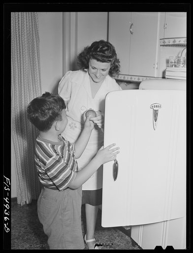 Brooklyn, New York. Red Hook housing project. Mrs. Caputo giving her son Jimmy an apple from the refrigerator