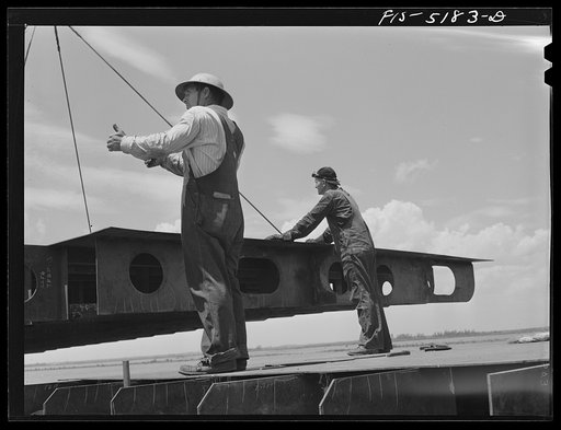Decatur, Alabama. Ingalls Shipbuilding Company. Lowering into place a section of the barge's doublebottom. This signal means "lift'er up, boom up"