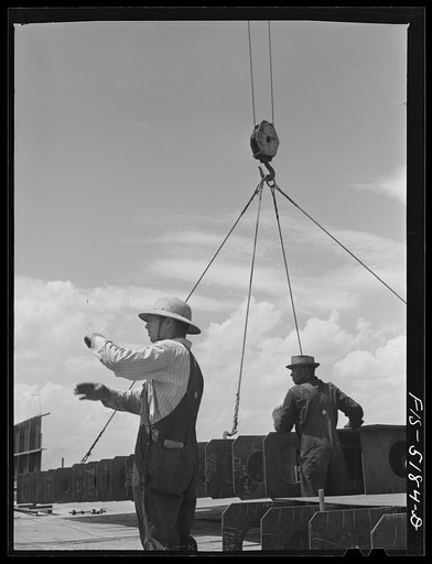 Untitled photo, possibly related to: Decatur, Alabama. Ingalls Shipbuilding Company. A section of a ship's bottom being lowered into place. The signal means "let'er down easy"