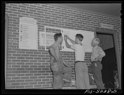 Untitled photo, possibly related to: Decatur, Alabama. Ingalls Shipbuilding Company. Morris Black, timekeeper, going off to the army, pinning his badge on the bulletin board carrying the names of other men from the yard who have joined the armed forces