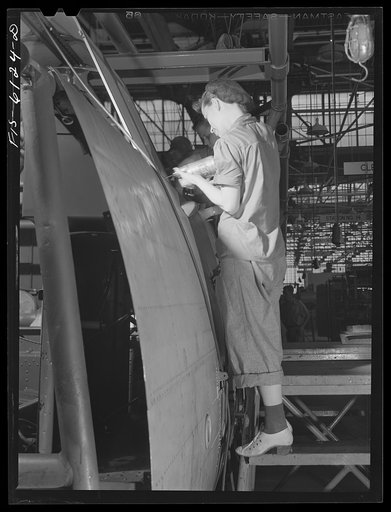 Woman riveter at work on the fuselage of a bomber at the Vultee Aircraft Corporation plant