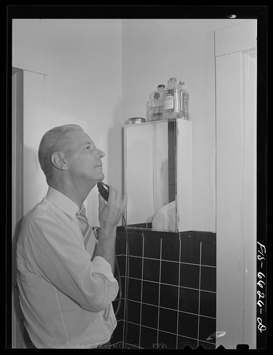 Untitled photo, possibly related to: Hayti, Missouri. President of the U.S. Rural Electrification Administration (REA) cooperative using an electric shaver