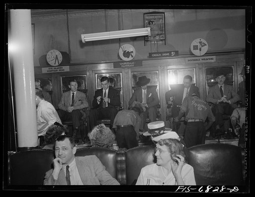 Untitled photo, possibly related to: New York, New York. Shoeshine parlor on East Forty-Second Street. Customers in the foreground are waiting while their shoes are repaired