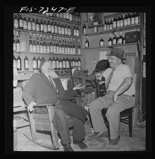 New York, New York. Rabbi in the Jewish section passing the time of day with the proprietor of a kosher wine shop where sacrificial wines are sold