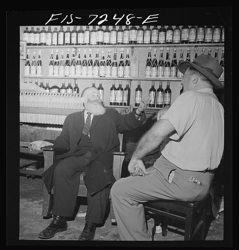 Untitled photo, possibly related to: New York, New York. Rabbi in the Jewish section passing the time of day with the proprietor of a kosher wine shop where sacrificial wines are sold