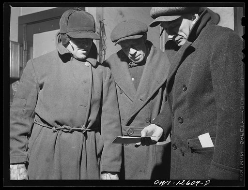 Chicago, Illinois. Yardmaster (right) going over the list of a train with two switchmen at a yard of the Chicago and Northwestern Railroad