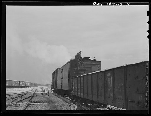 Chicago, Illinois. Switching cars in one of the Chicago and Northwestern Railroad classification yards. The switch man is braking the last two cars