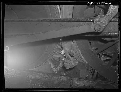 Untitled photo, possibly related to: Chicago, Illinois. Working on the underside of a locomotive in a pit at the roundhouse at the Chicago and Northwestern Railroad yard