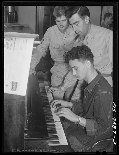Fort Belvoir, Virginia. A corporal picking out a tune on the piano while Sergeant George Camblair and a friend look on