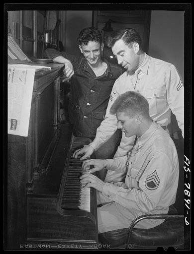 Fort Belvoir, Virginia. Sergeant George Camblair is taught how to play "chopsticks" on the piano in the recreation hall at his camp