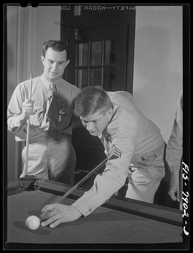 Fort Belvoir, Virginia. Sergeant George Camblair playing a game of billiards with friends in the recreation room at camp while waiting for mess call