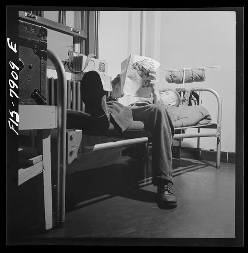 Fort Belvoir, Virginia. Sergeant George Camblair reading an article in a magazine while relaxing after dinner