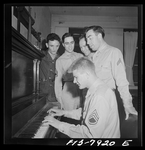 Untitled photo, possibly related to: Fort Belvoir, Virginia. Sergeant George Camblair is taught how to play "chopsticks" on the piano in the recreation hall at his camp