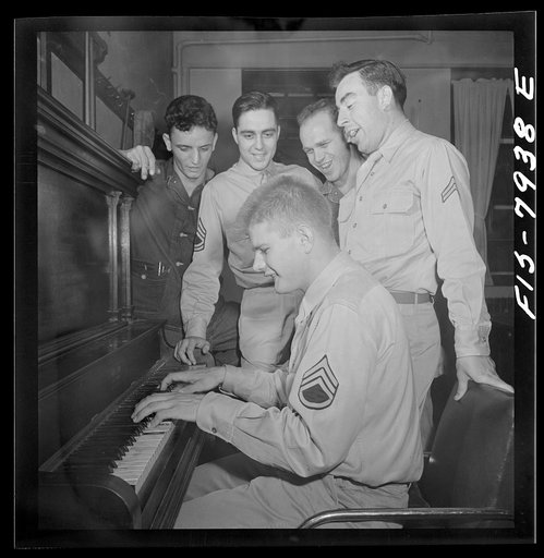 Fort Belvoir, Virginia. Sergeant George Camblair trying hard to provide an accompaniment for his friends' singing