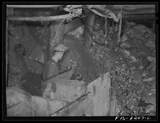 Butte, Montana. Anaconda Copper Mining Company. Miner using automatic mucking machine to load ore cars in a copper mine