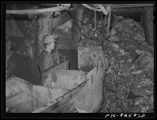 Butte, Montana. Anaconda Copper Mining Company. Miner using automatic mucking machine to load ore cars in a copper mine