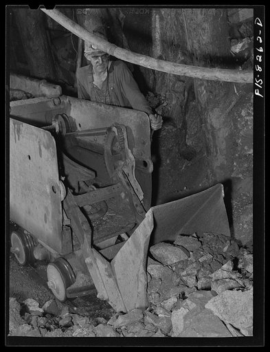 Butte, Montana. Anaconda Copper Mining Company. Miner using automatic mucking machine to load ore cars in a copper mine