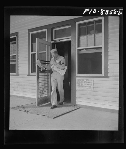 Fort Belvoir, Virginia. Sergeant George Camblair coming out of the post exchange with newspapers and ice cream