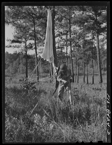 Untitled photo, possibly related to: Fort Bragg, North Carolina. Parachutists advancing through the woods after landing in a military demonstration