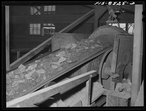 Anaconda smelter, Montana. Anaconda Copper Mining Company. Ore on conveyor belt just before reaching the Symons crusher; the magnet at end of belt removes metallic particles which have dropped into the ore during the mining process