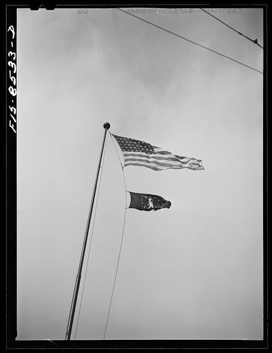 Untitled photo, possibly related to: Flag of Minutemen floats beneath the national flag. This minuteman flag signifies that over ninety percent of the workmen place ten percent of their wages in United States war bonds