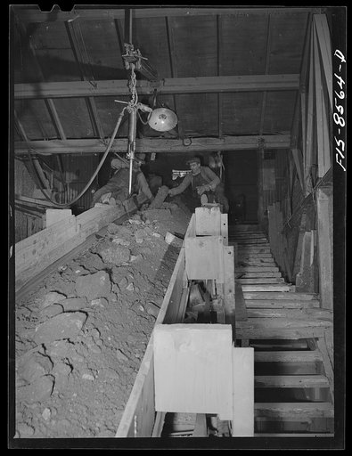 Untitled photo, possibly related to: Anaconda smelter, Montana. Anaconda Copper Mining Company. Two workmen remove wood and particles of timber from the mine-run ore as it is conveyed from the unloading bin to the first or gyratory crusher