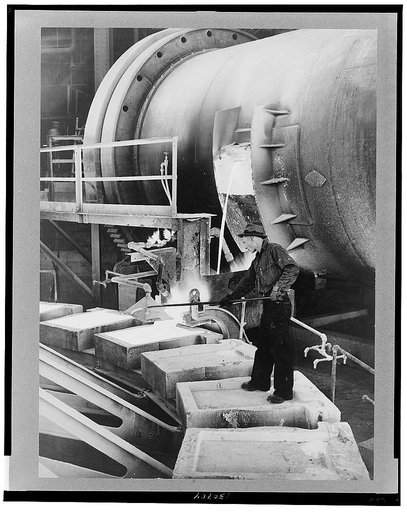Anaconda smelter, Montana. Anaconda Copper Mining Company. Pouring copper anodes from the refining furnace; forms are previously coated with bone-ash so that the copper anode can be more easily removed after cooling. The man standing in one of the forms is the sampler
