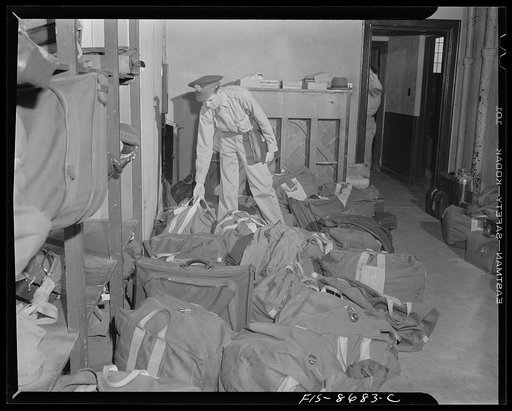 Wayne County Airport, a United States Army Air Corps air ferry command base sixteen miles from Detroit, Michigan. Lieutenant Benton selecting his parachute from the locker room