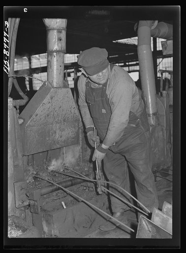 Great Falls, Montana. Anaconda Wire and Cable Company. Workmen putting unfinished rod into rolls of a finishing mill; from the wire bar to the finished rod, the processes of rolling are repeated so that the rod gets smaller and smaller until it is reduced to the desired size