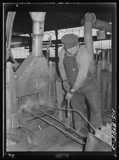 Great Falls, Montana. Anaconda Wire and Cable Company. Workmen putting unfinished rod into rolls of a finishing mill; from the wire bar to the finished rod, the processes of rolling are repeated so that the rod gets smaller and smaller until it is reduced to the desired size