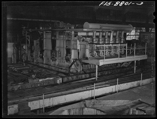 Untitled photo, possibly related to: Great Falls, Montana. Anaconda Wire and Cable Company. Billet heating furnace and intermediate rolls where the copper wire bar, which is the blunt white bar in left center, is converted to the rod at its immediate right and further reduced to size of the shown in
