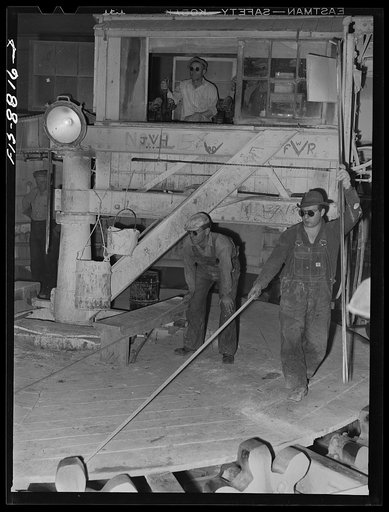 Great Falls, Montana. Furnace refinery of Anaconda Copper Mining Company. Control of the casting wheel is accomplished by the man in upper background; the two men on the casting wheel watch the level of copper as it is poured into molds; when the copper reaches an indicated level, the men raise thei