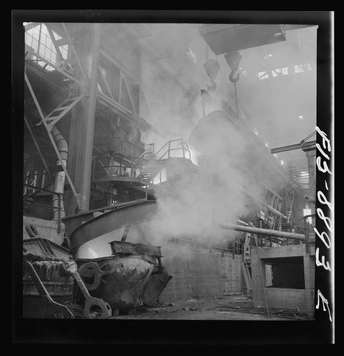 Anaconda smelter, Montana. Anaconda Copper Mining Company. In the lower left hand corner, copper from the reverbatory furnace is being poured into a ladle from which it will be carried to the converter; in the upper background, first pourings of slag from the converter are being poured back into the