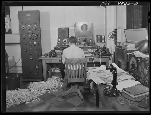 New York, New York. Radio room of the New York Times newspaper. The Times listening post, between 10 and 12 PM, between first and second editions. The operator is listening to Axis news (propaganda) broadcast. Paper in foreground has been previously examined to see what has already been covered in l