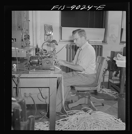 New York, New York. Radio room of the New York Times newspaper. The Times listening post, between 10 and 12 PM, between first and second editions. The operator is listening to Axis news (propaganda) broadcast. Paper in foreground has been previously examined to see what has already been covered in l