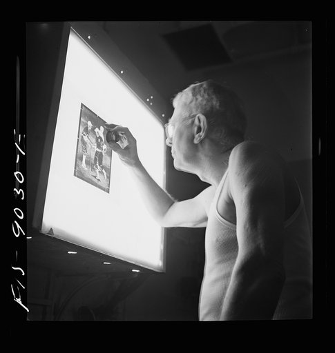 New York, New York. Photo engraving department of the New York Times newspaper. Examining the dots on the screen of a strip negative in the darkroom before it is transferred to a zinc plate