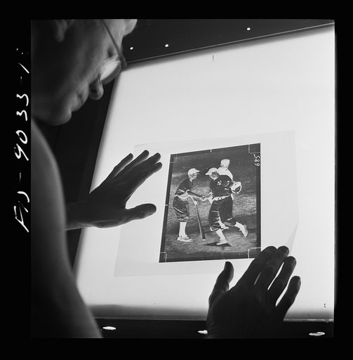 New York, New York. Photo engraving department of the New York Times newspaper. Examining the dots on the screen of a strip negative in the darkroom before it is transferred to a zinc plate