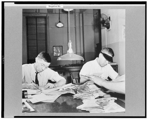 New York, New York. Newsroom of the New York Times newspaper. Copyreaders at the foreign desk. In foreground, foreign desk editor "spikes" a story (i.e. discards it)