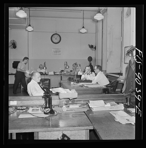 New York, New York. Newsroom of the New York Times newspaper. The "bull pen" where managing editors and others sit at one side. In foreground, assistant managing editor Rae. In background, managing editor James and night managing editor McCaw conferring