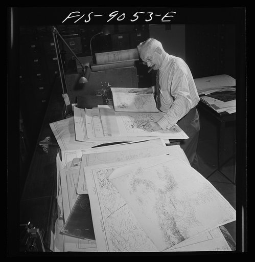 New York, New York. Art department of the New York Times newspaper. Cartographer consults key maps filed for reference in making maps for paper. This man here during last war; claims he can keep at least two countries ahead of the war