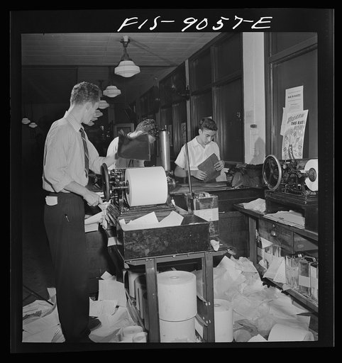 New York, New York. Wire room of the New York Times newspaper. Copy boys mimeograph all incoming dispatches which are then passed through slot into newsroom