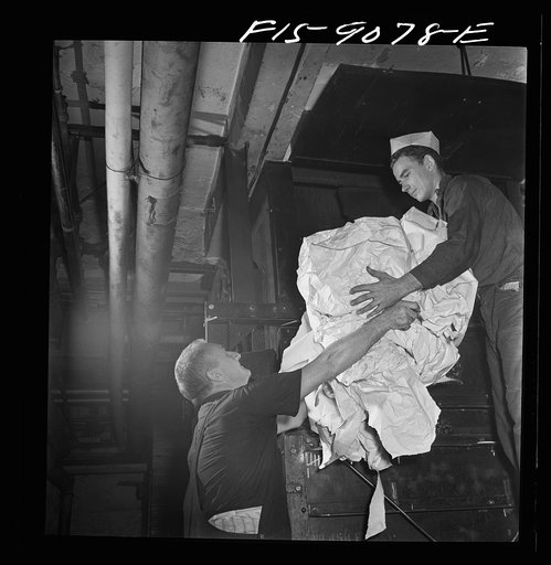 New York, New York. Reel room of the New York Times newspaper. Waste paper is picked up off floor, placed in bins, baled and sold to the government for scrap. This young boy is an apprentice, or "fly boy"