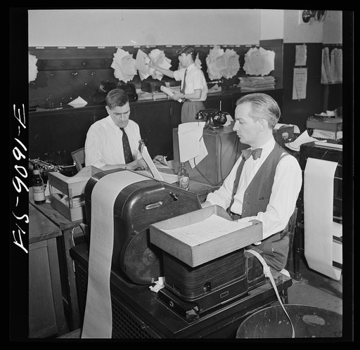 New York, New York. New York Times newspaper syndicate. Correspondents of American newspapers which are syndicate members. In background, copy boy posts Times dispatches